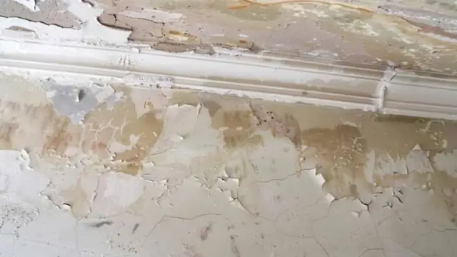 Water damaged wall with peeling paint and a stained baseboard