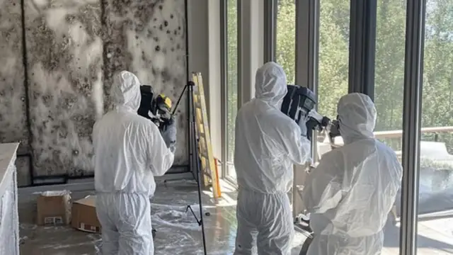 Remediation crew in protective suits and respirators working in a room